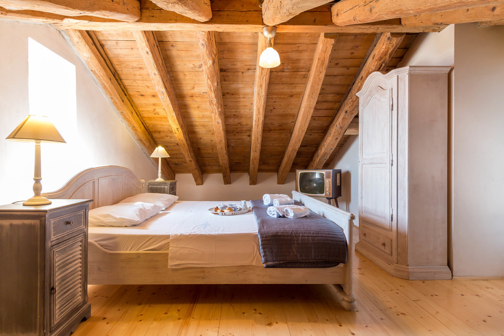 Esempio di un'In mansarda camera da letto mediterranea con pareti bianche e pavimento in legno massello medio