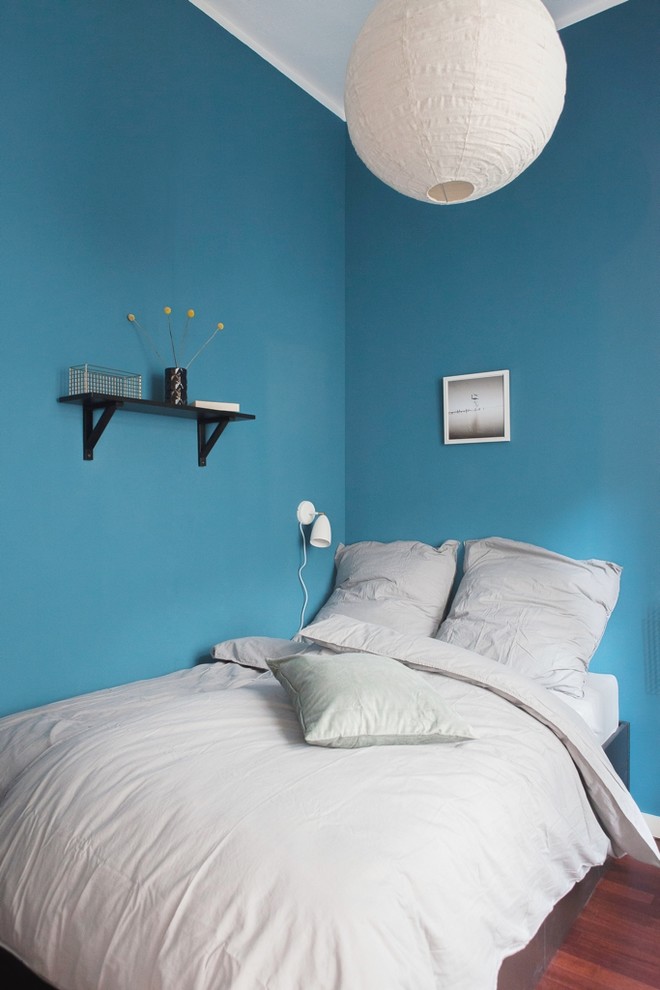 Modernes Schlafzimmer mit blauer Wandfarbe und dunklem Holzboden in Berlin