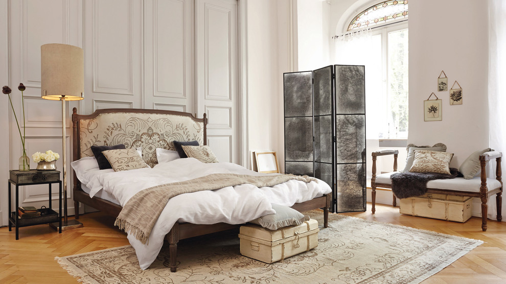 Modelo de dormitorio principal clásico extra grande sin chimenea con paredes blancas y suelo de madera en tonos medios