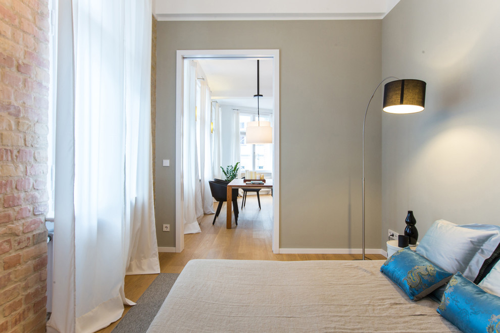 Cette image montre une petite chambre d'amis design avec un mur gris, parquet clair, aucune cheminée et un sol marron.
