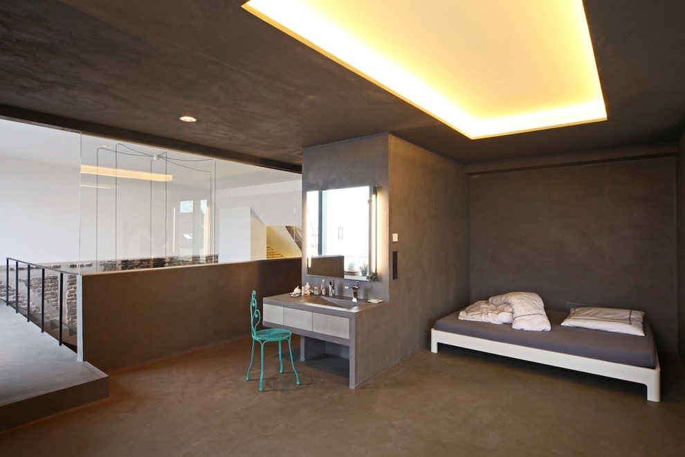 Foto på ett industriellt sovrum, med grå väggar och betonggolv