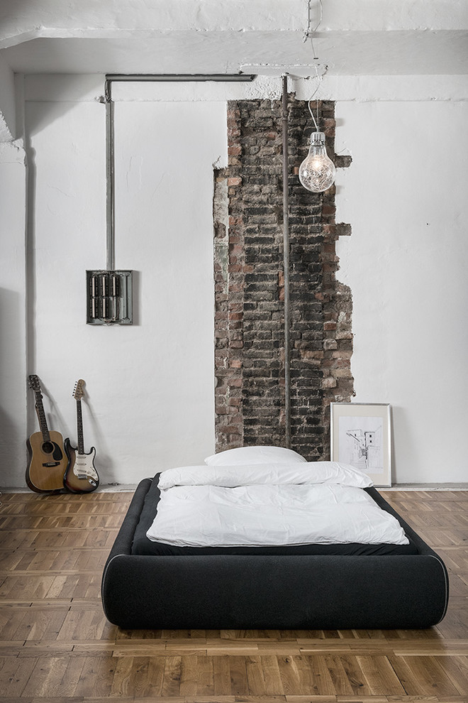 Großes Industrial Schlafzimmer ohne Kamin mit weißer Wandfarbe und braunem Holzboden in Sonstige