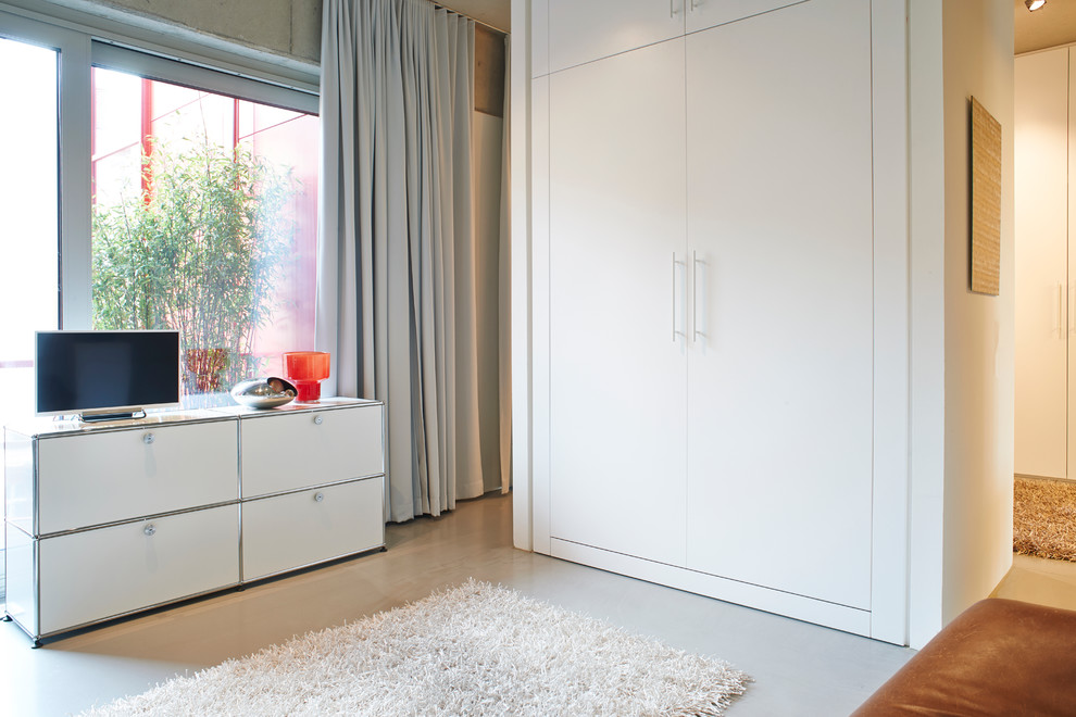 Geräumiges Industrial Schlafzimmer im Loft-Style mit grauer Wandfarbe, Betonboden und grauem Boden in Berlin