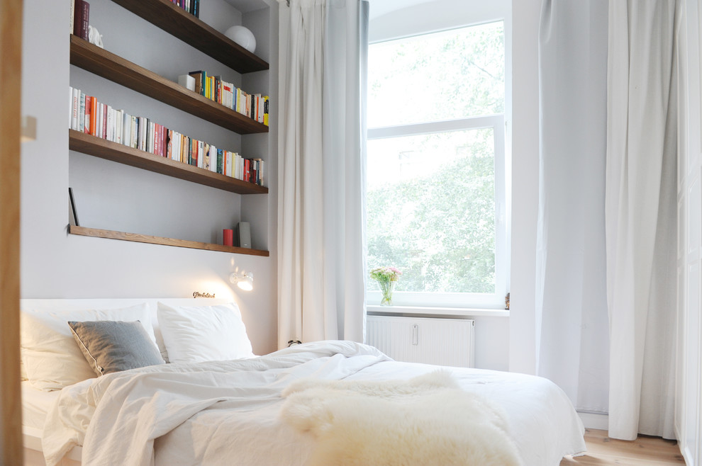 Imagen de dormitorio contemporáneo de tamaño medio con paredes blancas y suelo de madera clara