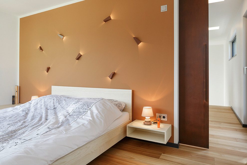 На фото: спальня среднего размера в современном стиле с оранжевыми стенами и паркетным полом среднего тона без камина