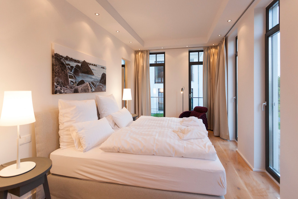 Bedroom - large contemporary master medium tone wood floor bedroom idea in Hamburg with white walls and no fireplace