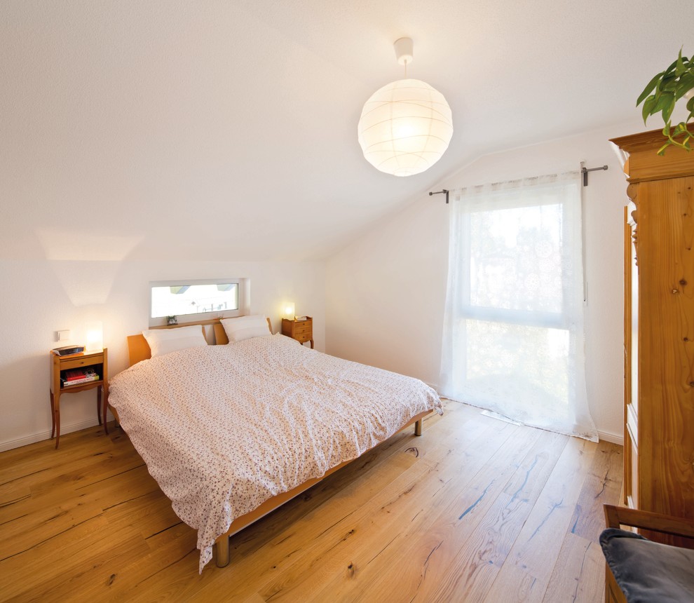 Country Hauptschlafzimmer mit weißer Wandfarbe, gebeiztem Holzboden und braunem Boden in Sonstige