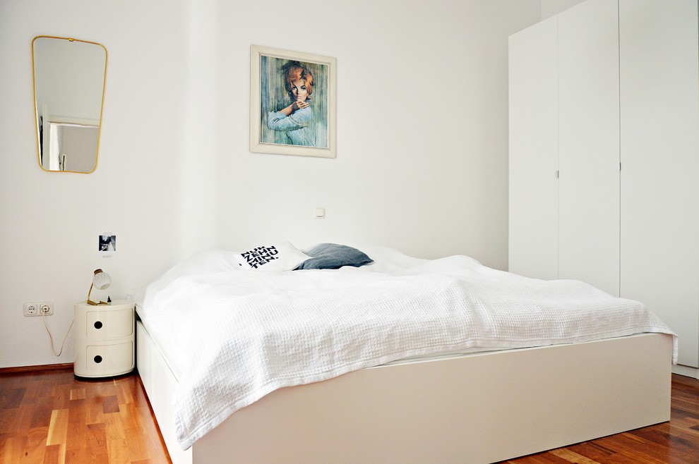 Modelo de dormitorio principal contemporáneo de tamaño medio sin chimenea con paredes blancas y suelo de madera en tonos medios