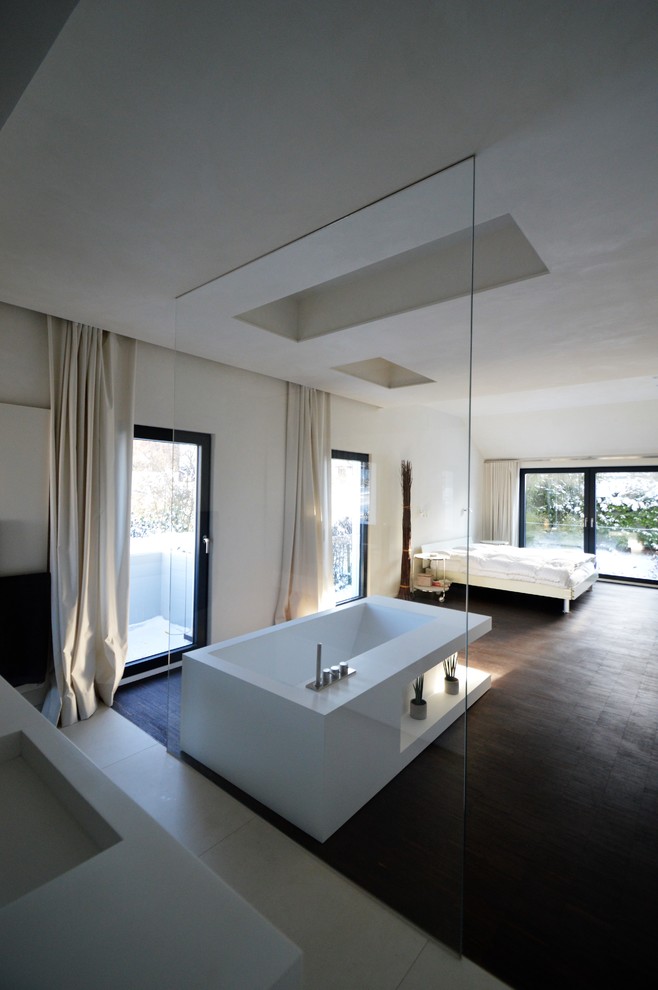 Immagine di un'ampia camera matrimoniale minimalista con pareti bianche, pavimento in legno massello medio, nessun camino e pavimento marrone