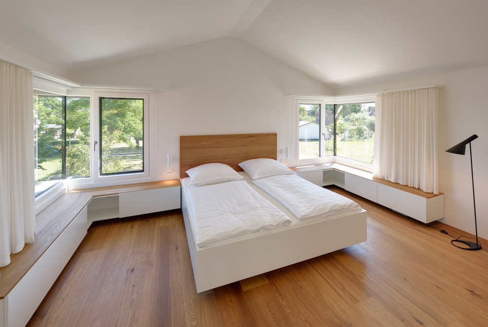 Mittelgroßes Modernes Hauptschlafzimmer ohne Kamin mit weißer Wandfarbe und braunem Holzboden in Berlin