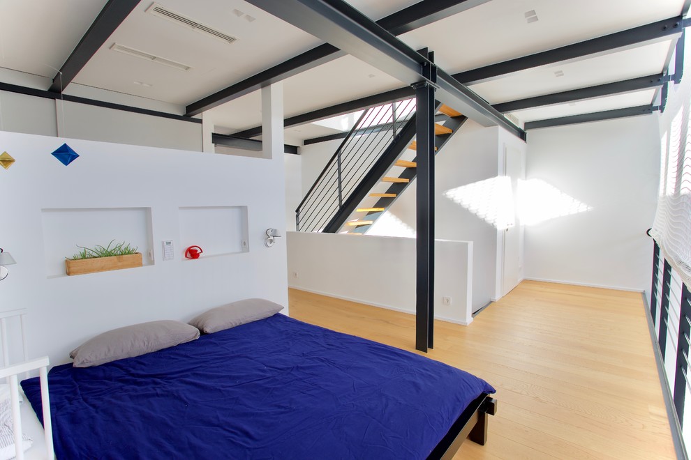 Großes Modernes Schlafzimmer im Loft-Style mit weißer Wandfarbe, hellem Holzboden und gelbem Boden in Düsseldorf