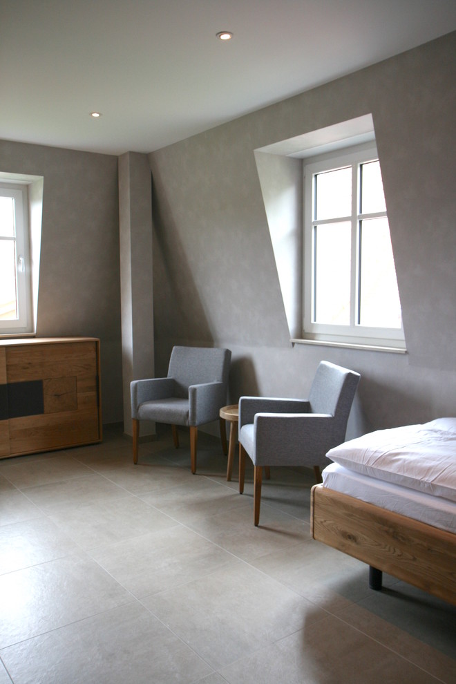 Modern inredning av ett mellanstort gästrum, med grå väggar, klinkergolv i keramik och grått golv