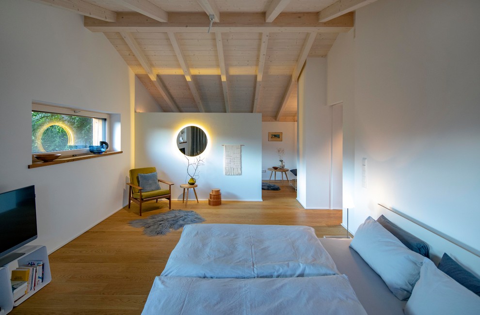Modernes Hauptschlafzimmer mit braunem Holzboden und freigelegten Dachbalken in München