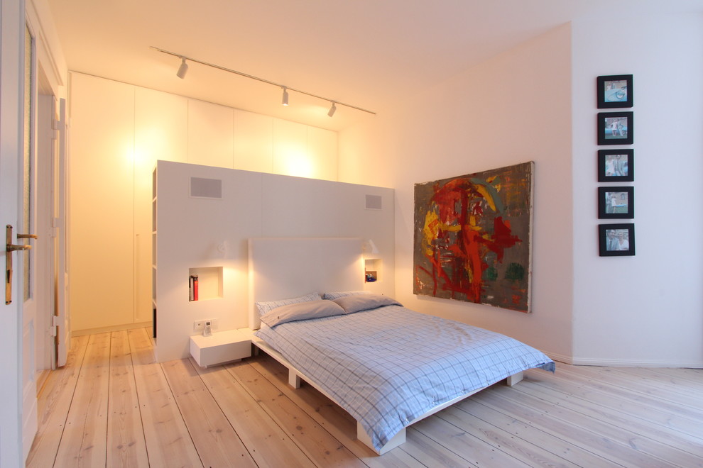 Großes Skandinavisches Hauptschlafzimmer ohne Kamin mit weißer Wandfarbe und hellem Holzboden in Berlin