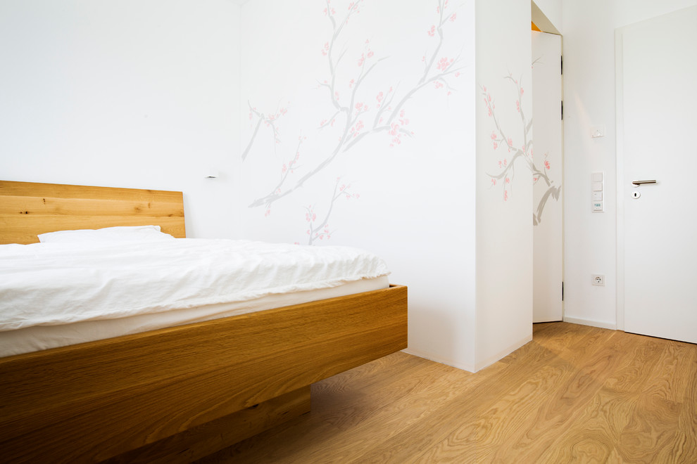 Foto de dormitorio principal contemporáneo de tamaño medio con suelo de madera en tonos medios, paredes blancas y suelo marrón