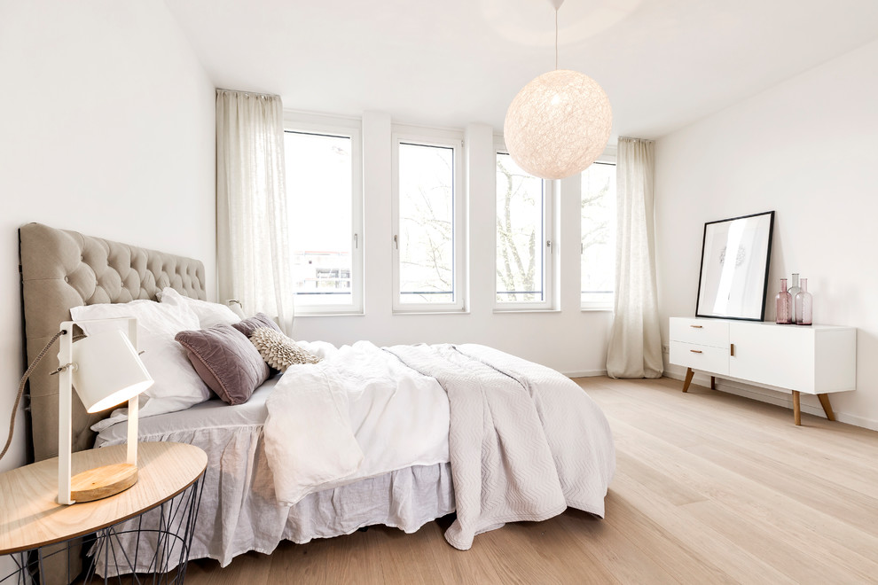 На фото: большая хозяйская спальня в скандинавском стиле с белыми стенами, светлым паркетным полом и коричневым полом без камина