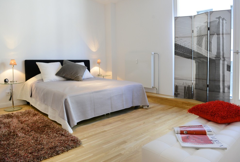 Modernes Schlafzimmer ohne Kamin mit weißer Wandfarbe und hellem Holzboden in Berlin