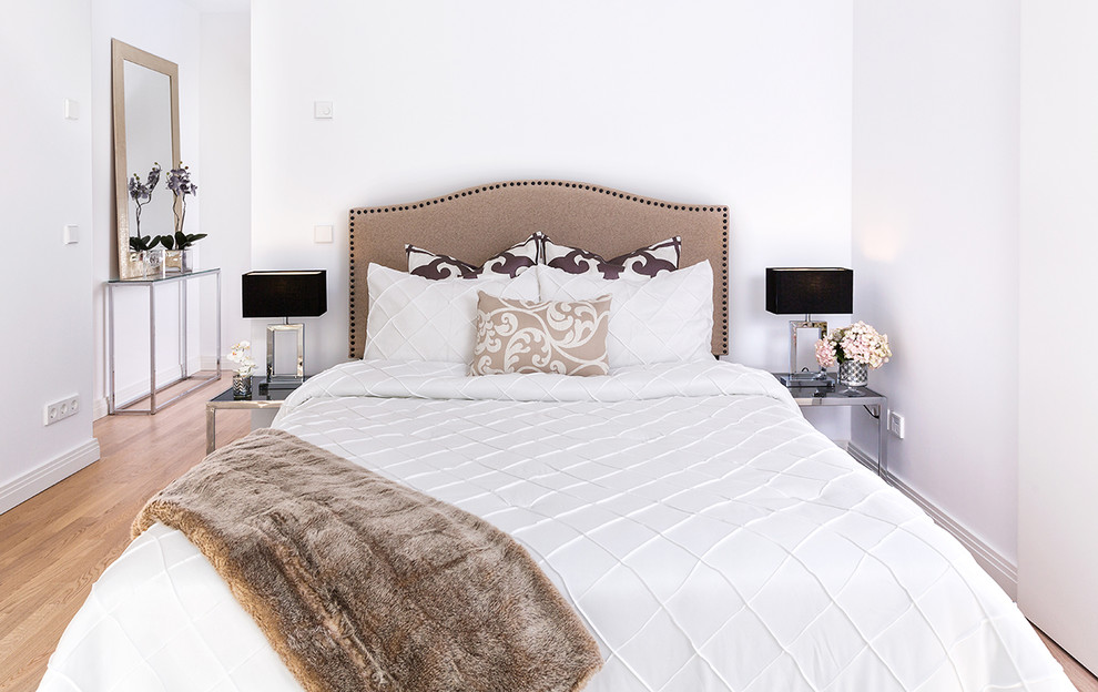 Imagen de dormitorio principal contemporáneo de tamaño medio con paredes blancas, suelo de madera en tonos medios y suelo marrón