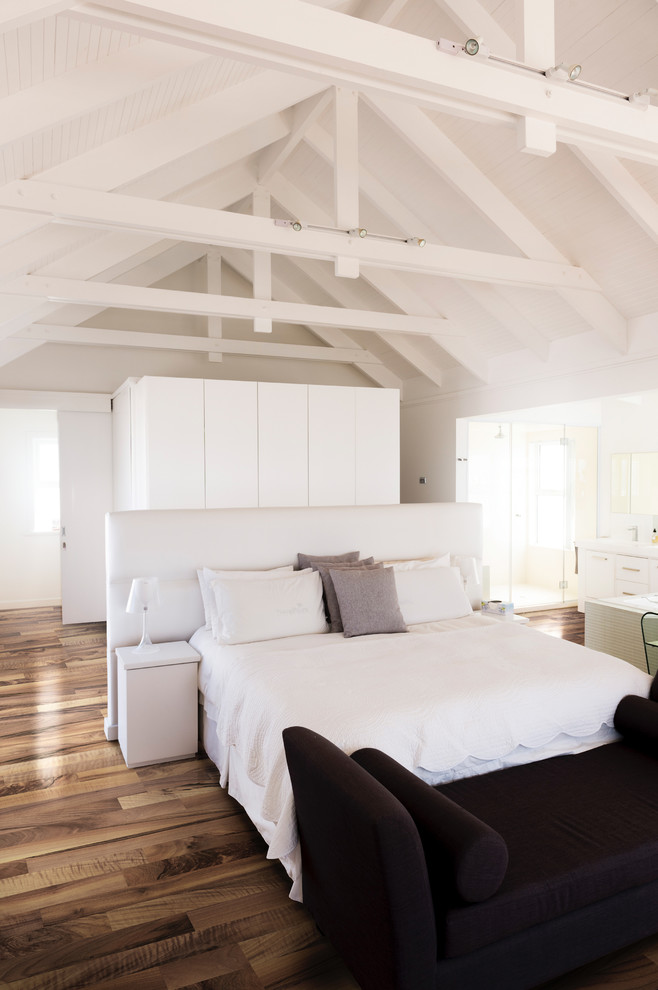 Modelo de dormitorio principal actual grande con paredes blancas y suelo de madera en tonos medios