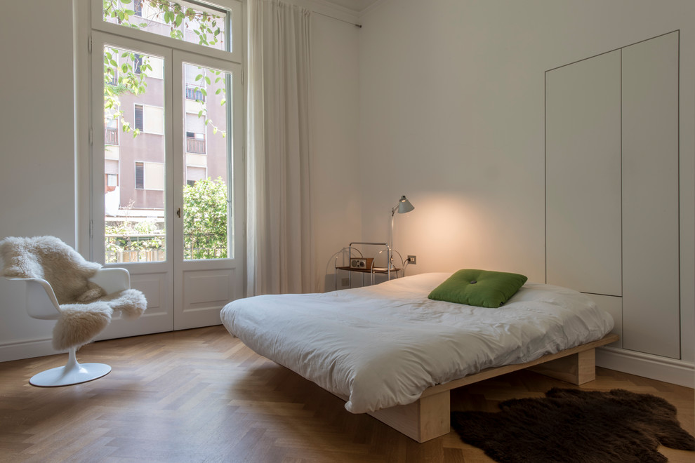 Imagen de dormitorio contemporáneo pequeño con paredes blancas y suelo de madera en tonos medios