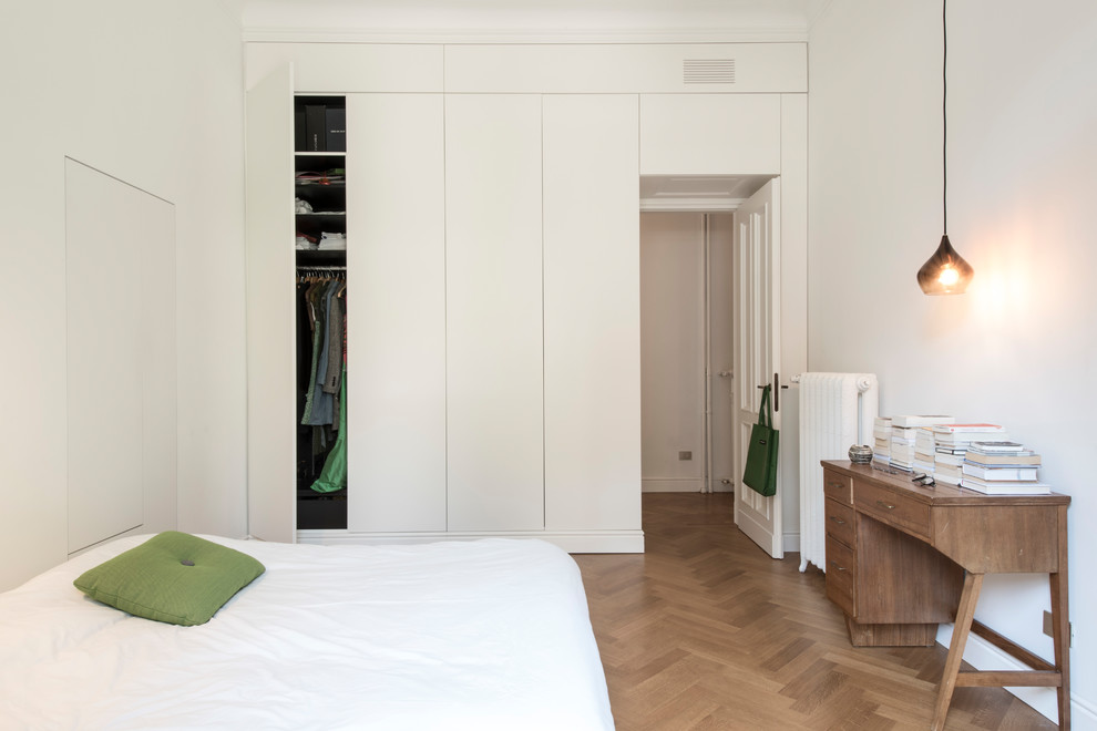 Kleines Modernes Schlafzimmer mit weißer Wandfarbe und braunem Holzboden in Mailand
