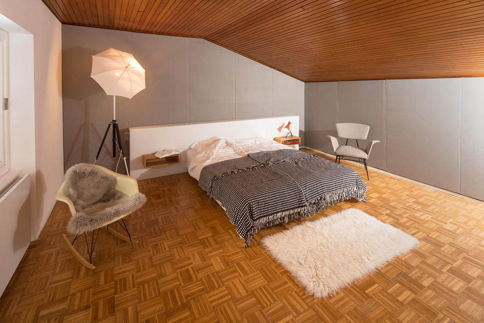 Bild på ett stort funkis sovrum, med grå väggar och mellanmörkt trägolv