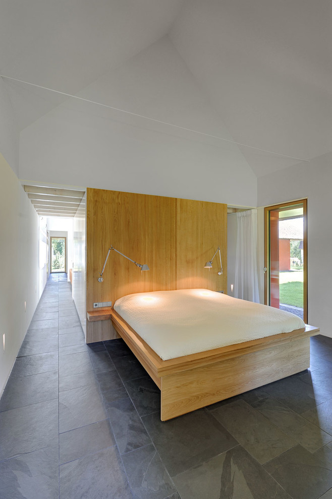 На фото: хозяйская спальня среднего размера в современном стиле с белыми стенами и полом из сланца без камина
