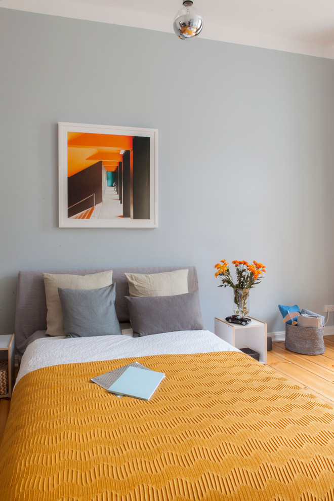 Foto de dormitorio urbano de tamaño medio sin chimenea con paredes grises y suelo de madera en tonos medios
