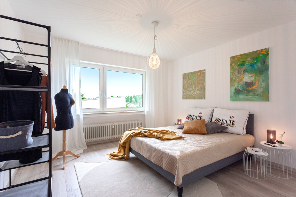 Modernes Schlafzimmer mit weißer Wandfarbe, braunem Holzboden und grauem Boden in Köln