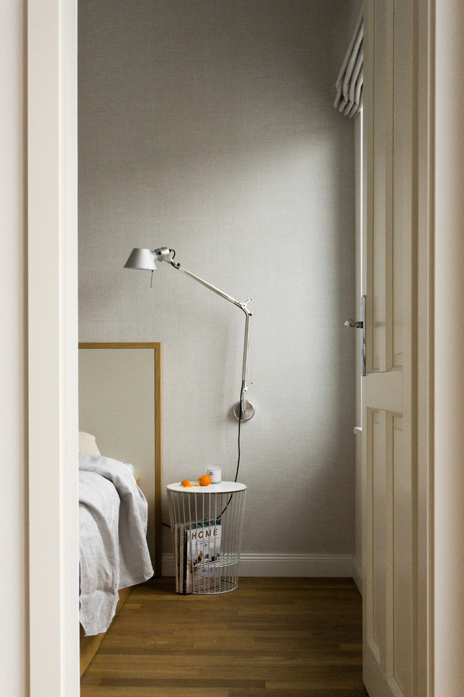 Esempio di una piccola camera matrimoniale minimalista con pareti grigie, pavimento in legno massello medio e pavimento marrone