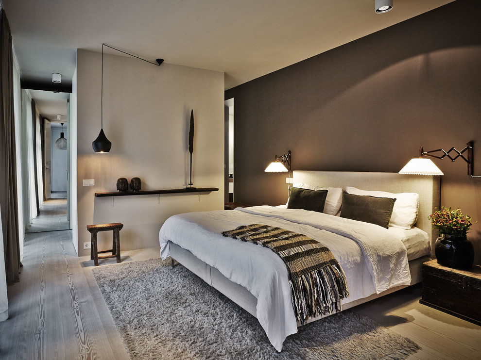 Immagine di una camera da letto nordica con pavimento in legno verniciato e pareti grigie