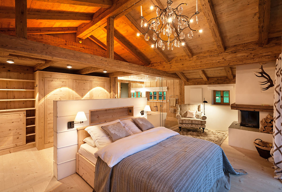 Mittelgroßes Landhaus Hauptschlafzimmer mit weißer Wandfarbe, hellem Holzboden, Eckkamin, verputzter Kaminumrandung und braunem Boden in München
