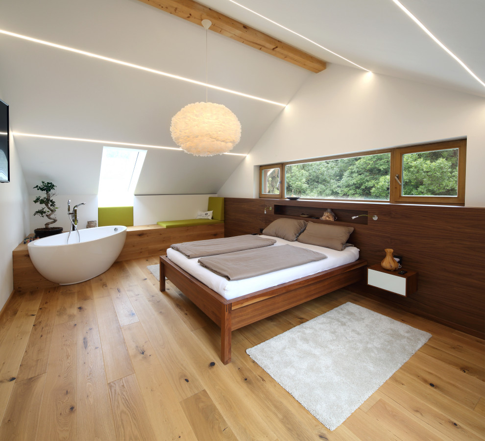 Photo of a large contemporary guest bedroom in Munich with white walls, light hardwood flooring and beige floors.