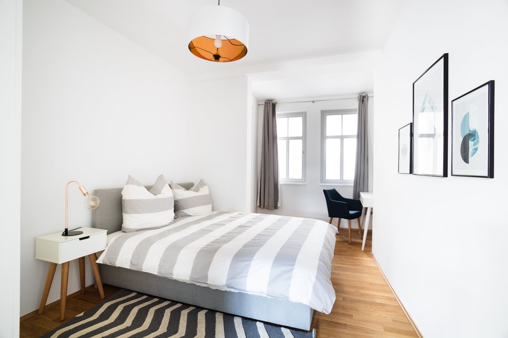 Ejemplo de habitación de invitados escandinava de tamaño medio sin chimenea con paredes blancas, suelo de madera en tonos medios y suelo marrón