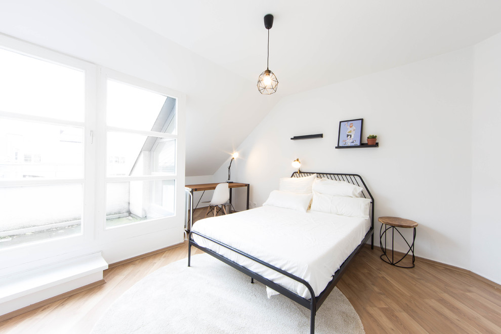 Foto de dormitorio principal nórdico de tamaño medio sin chimenea con paredes blancas, suelo de madera clara y suelo marrón