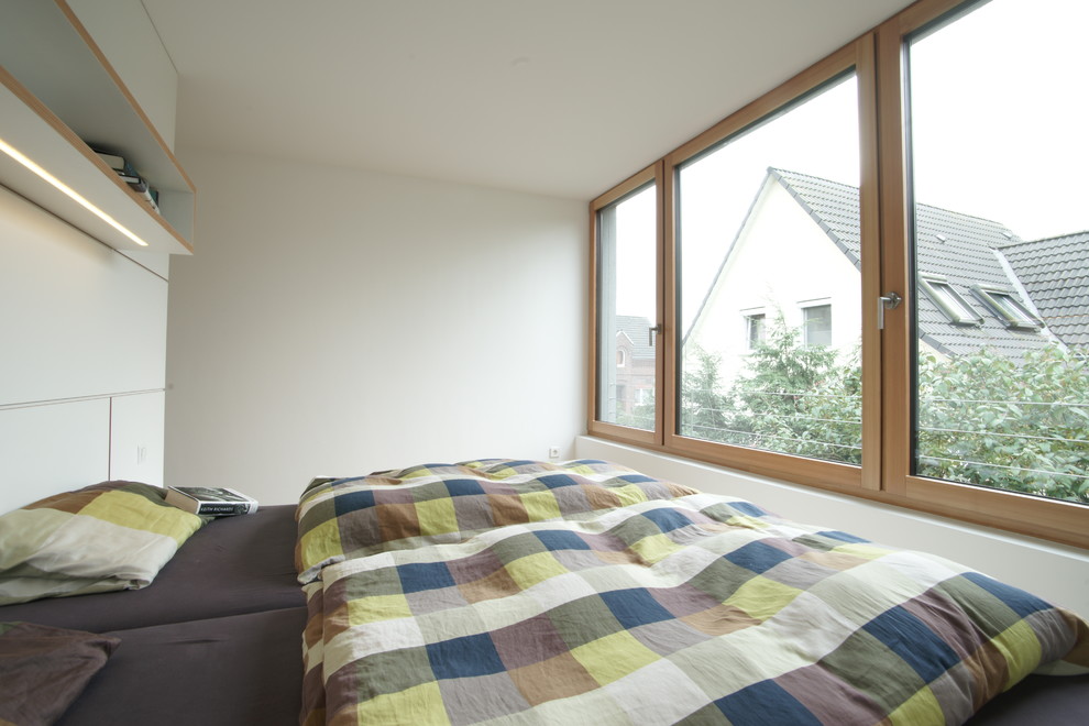 Immagine di una piccola camera matrimoniale minimalista con pareti bianche e pavimento in legno massello medio