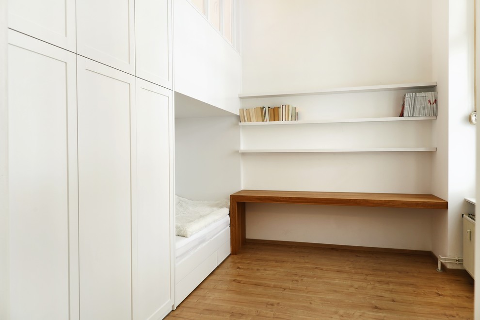 Ispirazione per una piccola camera degli ospiti minimalista con pareti bianche, parquet chiaro e pavimento marrone