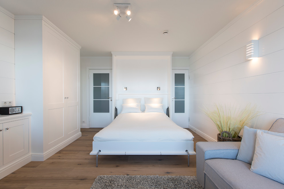 Großes Landhaus Hauptschlafzimmer ohne Kamin mit weißer Wandfarbe und braunem Holzboden in Sonstige