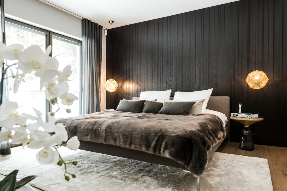 Immagine di una grande camera matrimoniale minimalista con pareti nere, pavimento in legno massello medio e nessun camino