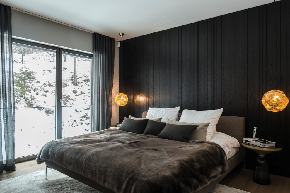 Foto de dormitorio principal actual de tamaño medio sin chimenea con paredes negras y suelo de madera en tonos medios