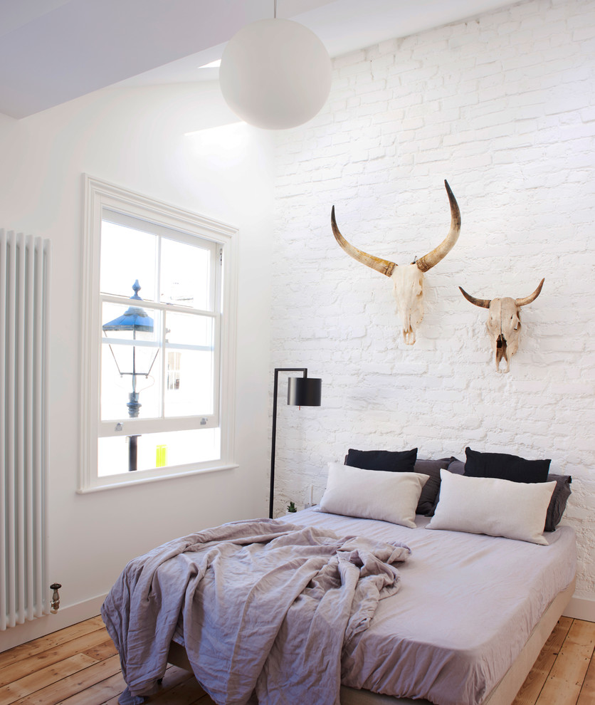 This is an example of a medium sized scandinavian master and grey and brown bedroom in London with white walls, no fireplace, brown floors and light hardwood flooring.