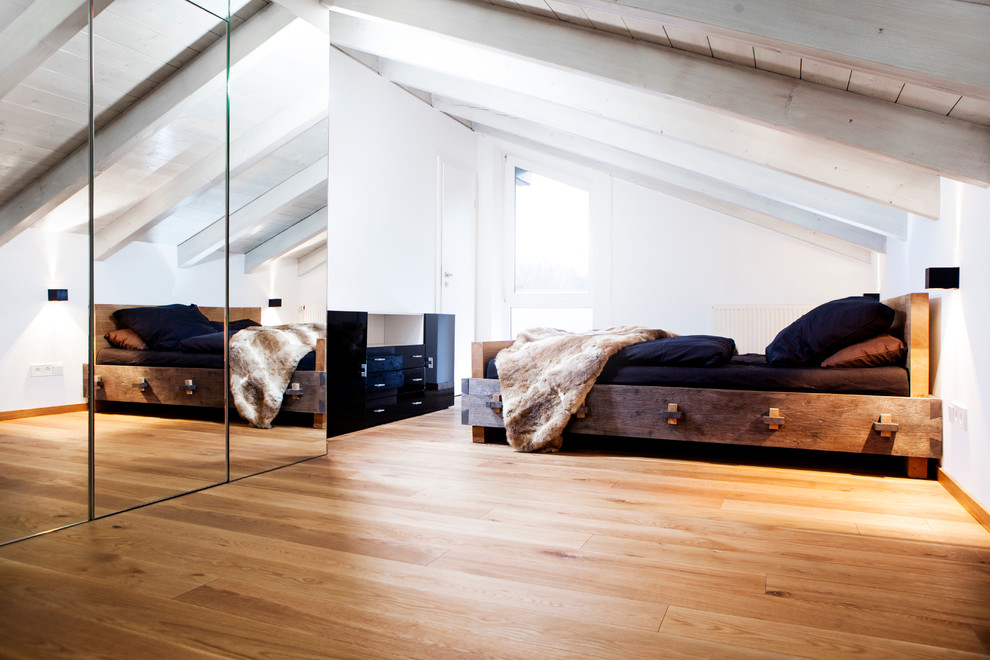 Imagen de dormitorio principal nórdico grande con paredes blancas, suelo de madera clara, estufa de leña, marco de chimenea de metal y suelo marrón