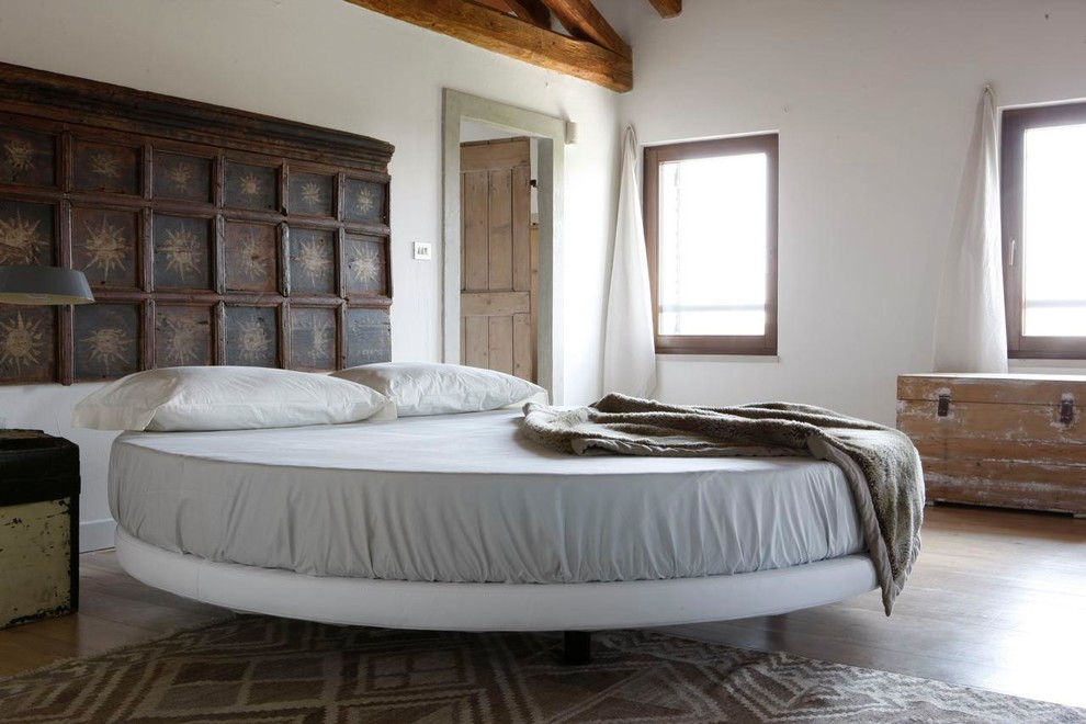 Aménagement d'une chambre parentale contemporaine avec un mur blanc, un sol en bois brun et aucune cheminée.