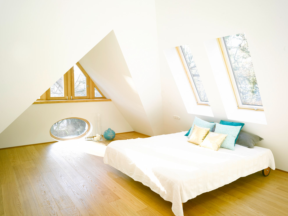 Cette image montre une chambre parentale design avec un mur blanc, un sol en bois brun et aucune cheminée.