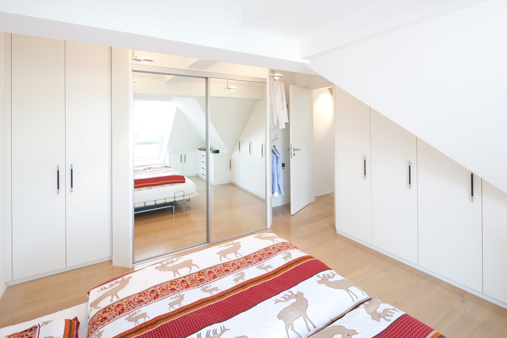 Idée de décoration pour une chambre parentale design de taille moyenne avec un mur blanc, parquet clair et un sol marron.