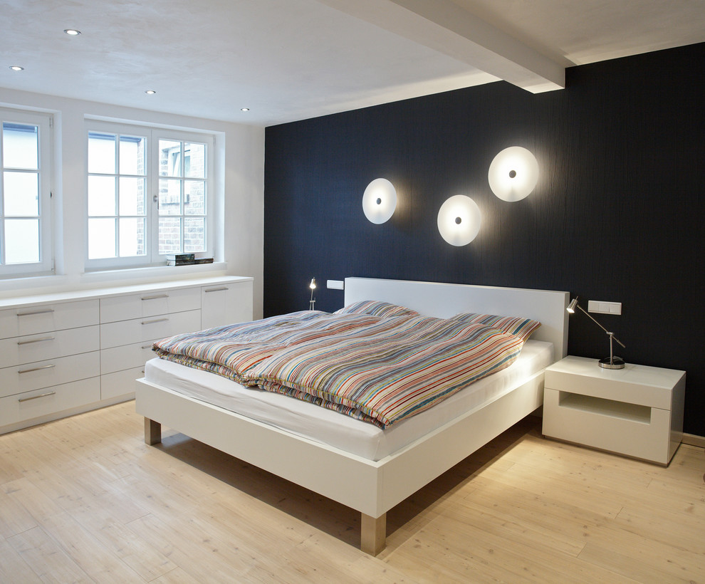 Mittelgroßes Modernes Hauptschlafzimmer ohne Kamin mit schwarzer Wandfarbe und hellem Holzboden in Bremen