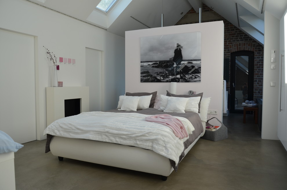 Идея дизайна: большая хозяйская спальня в современном стиле с белыми стенами, бетонным полом, стандартным камином и серым полом