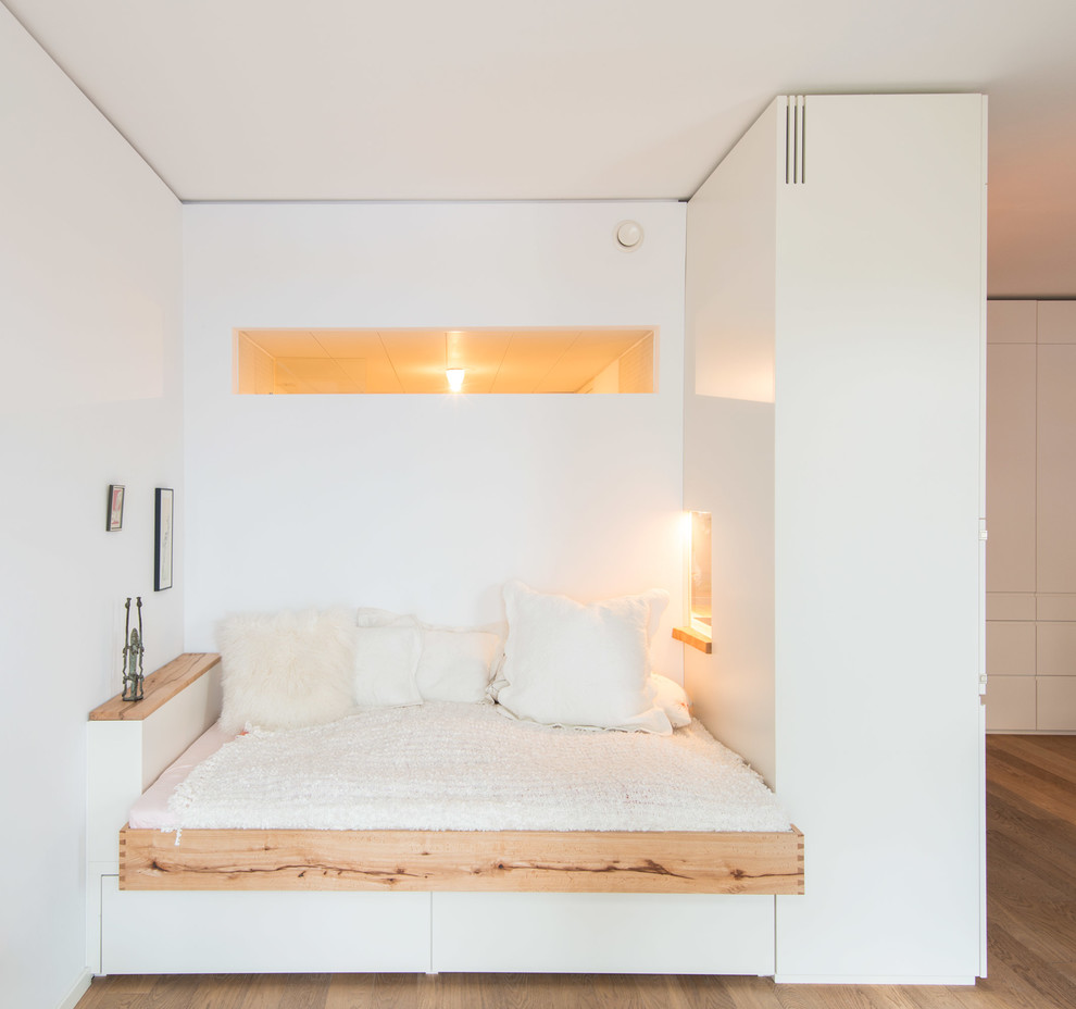 Aménagement d'une chambre d'amis contemporaine de taille moyenne avec un mur blanc, un sol en bois brun et aucune cheminée.