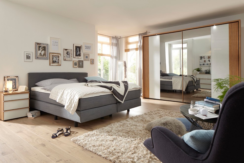 Großes Modernes Schlafzimmer ohne Kamin mit weißer Wandfarbe und hellem Holzboden in Dresden