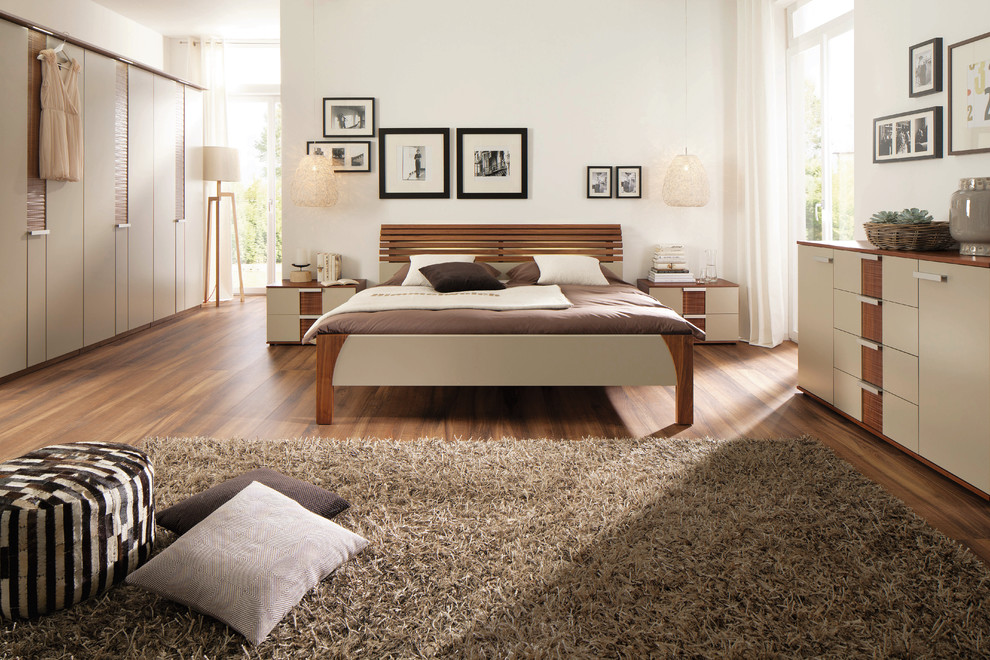 Example of a large trendy master medium tone wood floor bedroom design in Dresden with white walls and no fireplace